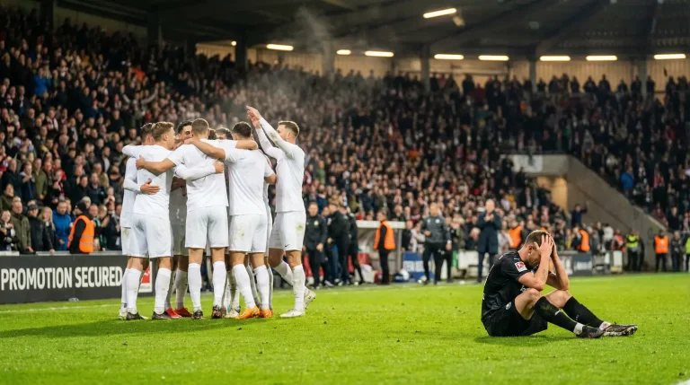 Fußballspieler auf dem Rasen zwischen Jubel und Enttäuschung nach einem Bundesliga-Aufstiegsspiel
